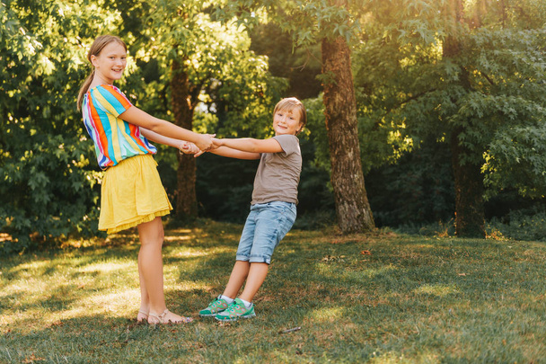 Группа из двух детей, играющих вместе в летнем парке, держащихся за руки, вращающихся вместе
 - Фото, изображение