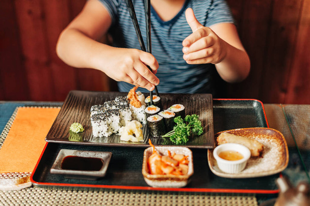 Cute kid boy eating sushi in asian restaurant - Fotó, kép