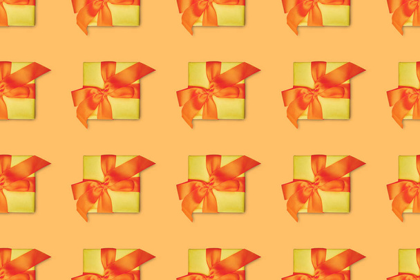 nahtloser orange Hintergrund mit gelben Weihnachtsgeschenken mit Schleifen - Foto, Bild