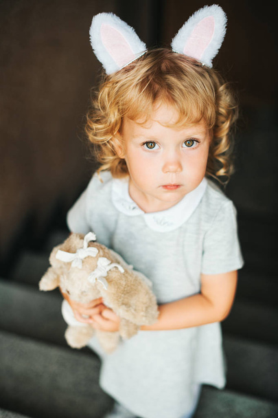 Portrait d'adorable jeune fille portant des oreilles de lapin, tenant jouet lapin doux
  - Photo, image