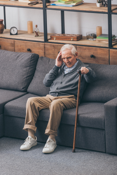retired man with grey hair having headache while sitting on sofa  - Zdjęcie, obraz