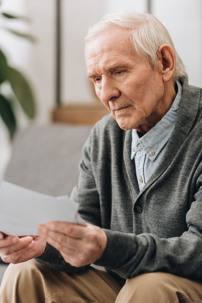Rentner mit grauen Haaren schaut sich zu Hause Fotos an - Foto, Bild