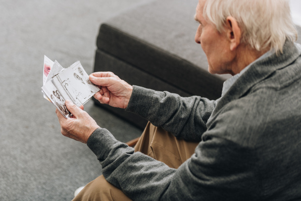 retired man with grey hair looking at old photos at home - Photo, Image