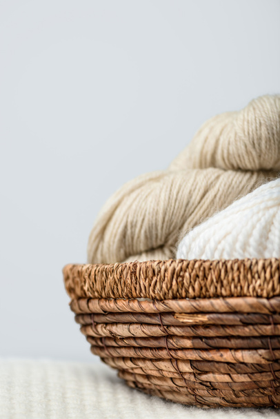 close up view of yarn clews in wicker basket on grey backdrop - Foto, immagini
