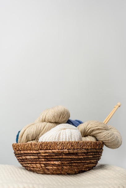 close up view of yarn clews in wicker basket on grey backdrop - Foto, immagini