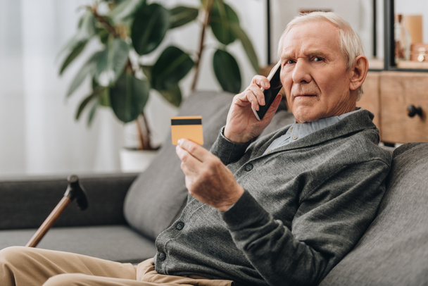 senior man talking on smartphone and holding credit card   - Foto, Bild