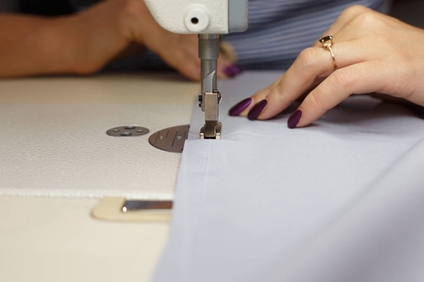 Vista dall'alto su mani di sarto femminile che lavora a macchina per cucire. abbigliamento industria manifatturiera. - Foto, immagini