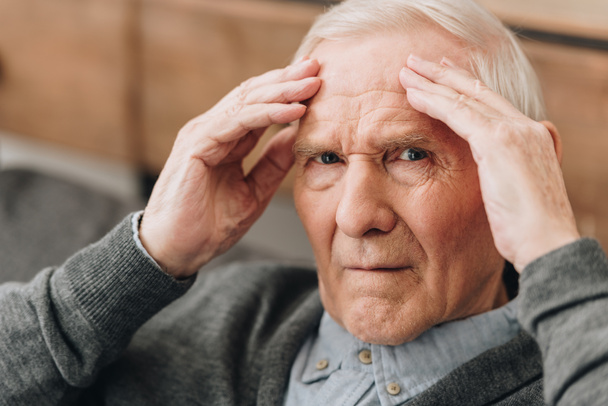 gepensioneerde man die hoofd terwijl het hebben van hoofdpijn  - Foto, afbeelding
