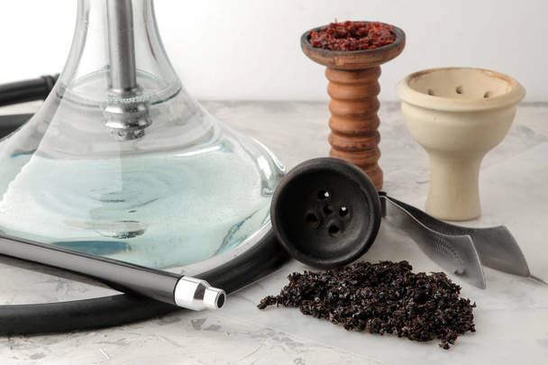 Átlátszó vízipipa fekete fúvóka és egy agyag edényben, a dohány és a különböző kiegészítők készítéséhez vízipipa a világos háttér. vízipipa tartozékok - Fotó, kép
