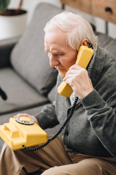 senior man talking on retro phone at home - Foto, Imagem