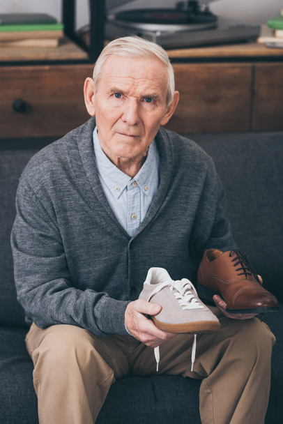 retired man choosing between classic and modern shoes - Фото, изображение