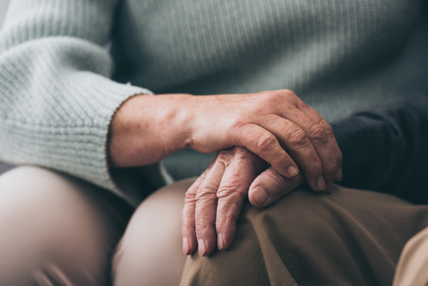Ausgeschnittene Ansicht einer Seniorin, die Händchen hält mit ihrem Ehemann im Ruhestand  - Foto, Bild