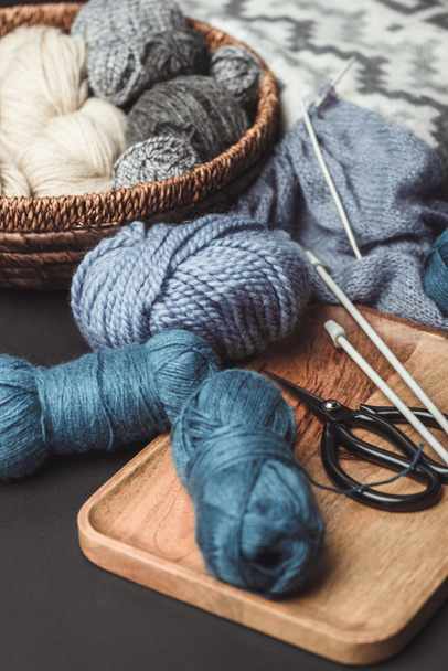 vue rapprochée du tricot, des ciseaux et des aiguilles à tricoter sur la table sombre avec couverture
 - Photo, image
