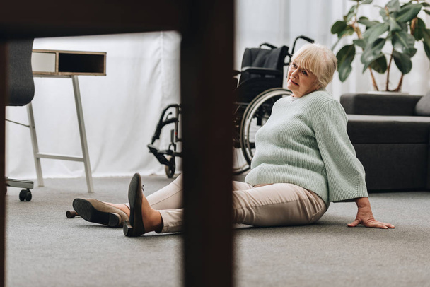 helpless retired woman sitting on floor near wheelchair  - Fotografie, Obrázek