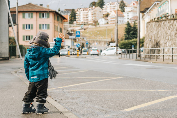 Klein kind verhogen van de hand op het busstation, foto genomen in Lausanne, Zwitserland - Foto, afbeelding