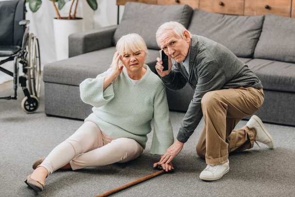 senior wife sitting on floor while retired husband talking on smartphone  - Foto, Bild