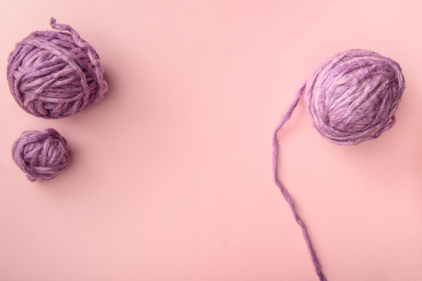 top view of purple knitting balls on pink tabletop - Fotó, kép