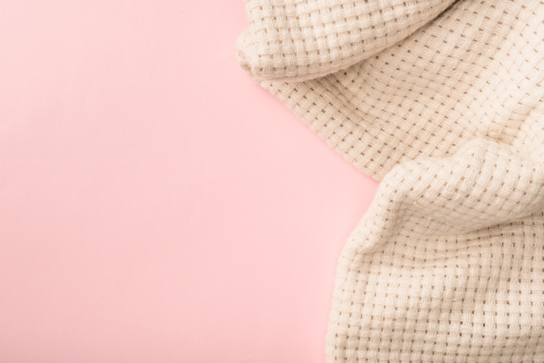 bovenaanzicht van wit gebreid deken op roze achtergrond - Foto, afbeelding