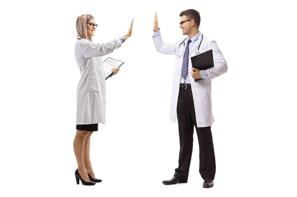 Full length shot of a male and female doctor gesturing high-five isolated on white background - Fotó, kép