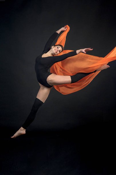 mooie jongedame atleet gymnast in beweging op zwarte achtergrond - Foto, afbeelding