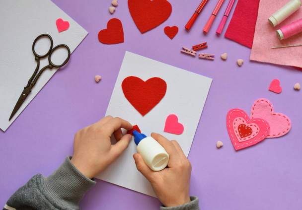 Making of handmade Valentine greeting card from felt. Children's DIY, hobby concept, gift with your own hands. Valentine's Day decoration. Step 3. Stick the heart template on card. - Φωτογραφία, εικόνα