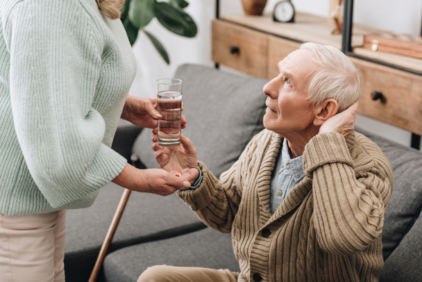 Senior kobieta pomaga do stary człowiek z laską i daje tabletki  - Zdjęcie, obraz