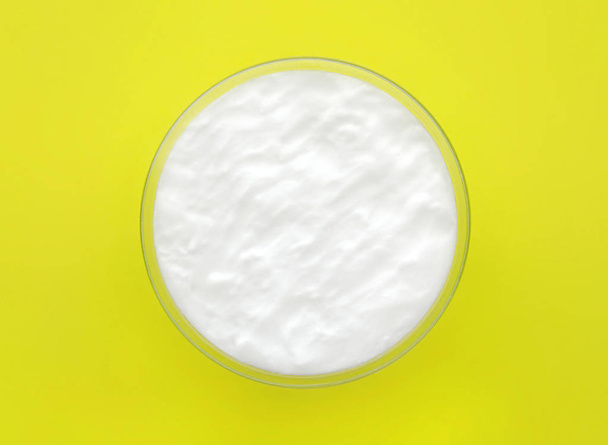 White cosmetic cream in glass container on yellow background. Top view. - Foto, Imagem