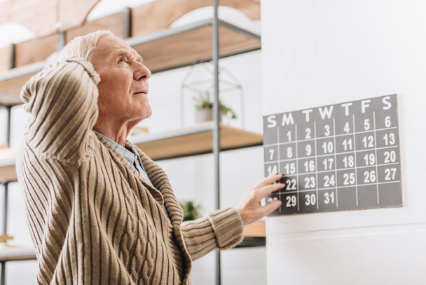 starší muž dotkl Nástěnný kalendář a hlavu - Fotografie, Obrázek