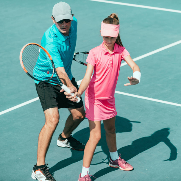Tennis instructor with young girl on tennis training - 写真・画像