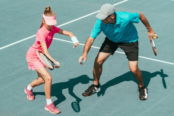 Instructor de tenis con niña en el entrenamiento de tenis
 - Foto, Imagen