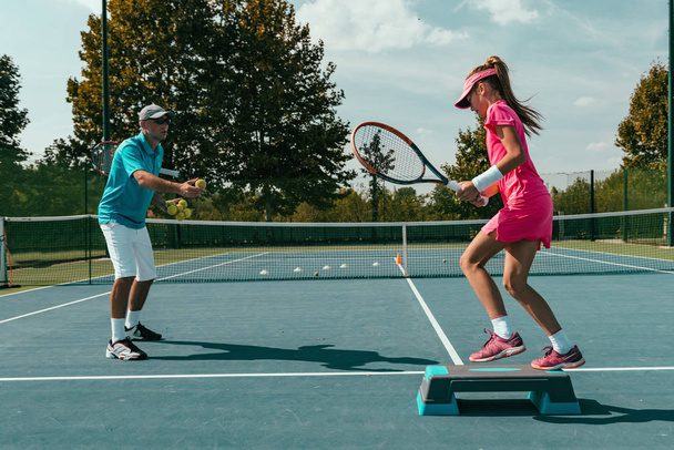 Tennis instructor with young girl on tennis training - Photo, Image