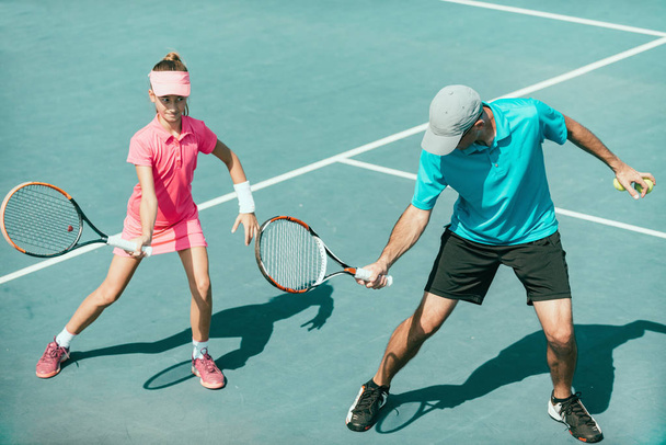 Tennis instructor with young girl on tennis training - Foto, Imagen