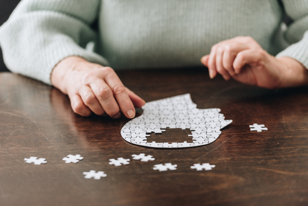 обрізаний вид на старшу жінку, що грає з головоломками на столі
 - Фото, зображення