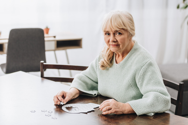 blonde retired woman playing with puzzles at home  - Foto, Imagem