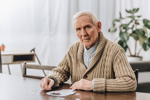 pensionista triste con el pelo gris jugando con rompecabezas en casa
  - Foto, imagen
