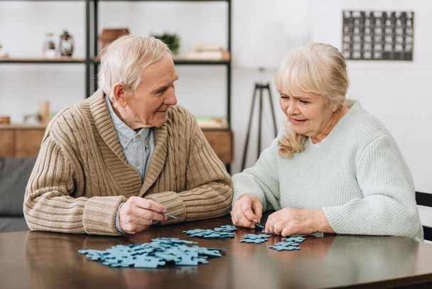 feliz pareja jubilada jugando con rompecabezas en casa
 - Foto, Imagen