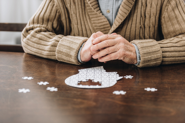 vista recortada del hombre retirado jugando con rompecabezas en la mesa
 - Foto, Imagen