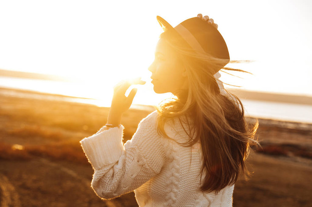 Beautiful young woman walking outdoors at the beach during sunset - Foto, afbeelding