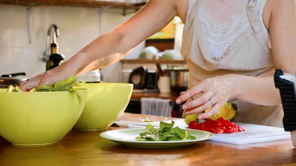 Young woman preparing a salad. Cook put herbs in plate for salad - Фото, изображение