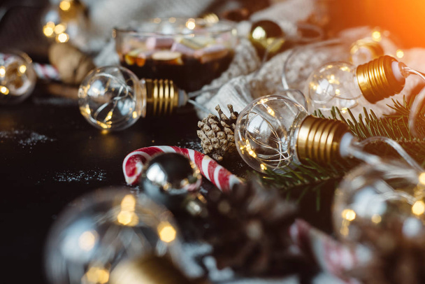 Christmas background with festive decoration, candy and the garland on a dark background with warm rays of the sun. - Photo, Image