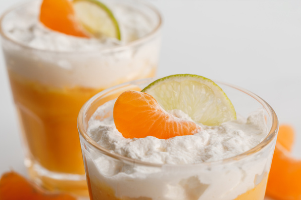 primer plano de dos vasos de postres de crema con rebanadas de mandarina y lima
 - Foto, Imagen
