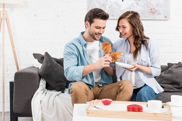 happy couple eating croissants during breakfast at home  - Foto, imagen