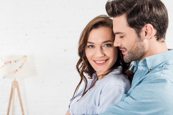 portrait of man embracing smiling woman at home  - Photo, image