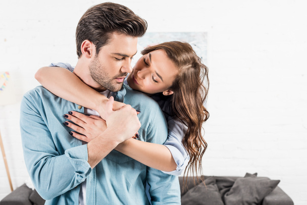 attractive woman hugging man from behind at home - Foto, imagen