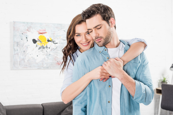 beautiful smiling woman hugging man from behind at home - Fotoğraf, Görsel
