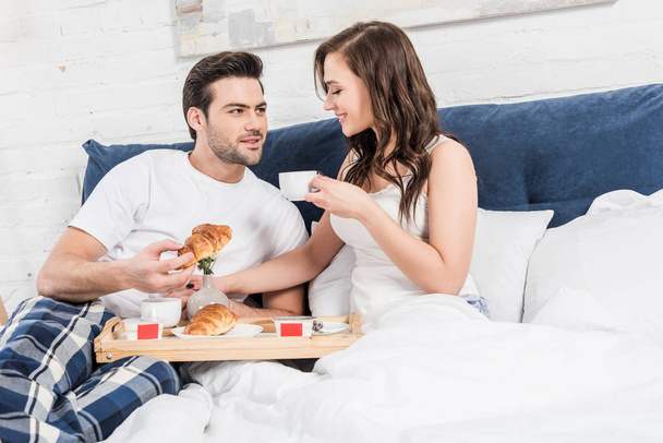 couple lying in bed and having breakfast in morning at home  - Foto, afbeelding