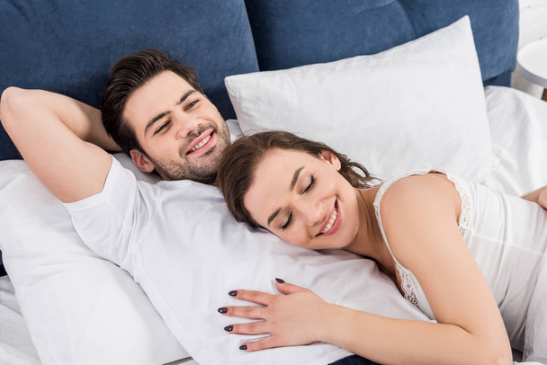beautiful smiling couple cuddling in bed at home - Foto, imagen