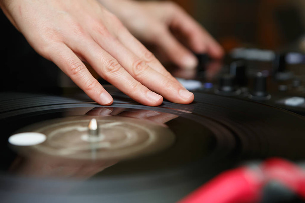Djs hand scratch vinyl record on turn table.Professional night club turntables record player in focus.Party dj audio equipment setup.Play tracks,scratch records at night adult entertainment event  - Foto, Bild