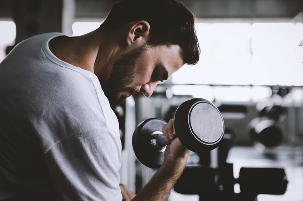 Крупный план мужчины здоровые проведение гантели тренировки и строительство тела в тренажерном зале фитнес
 - Фото, изображение