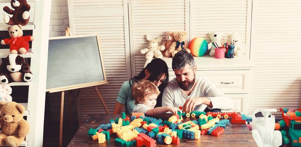 Family and childhood concept. Young family spends time in playroom - Photo, Image